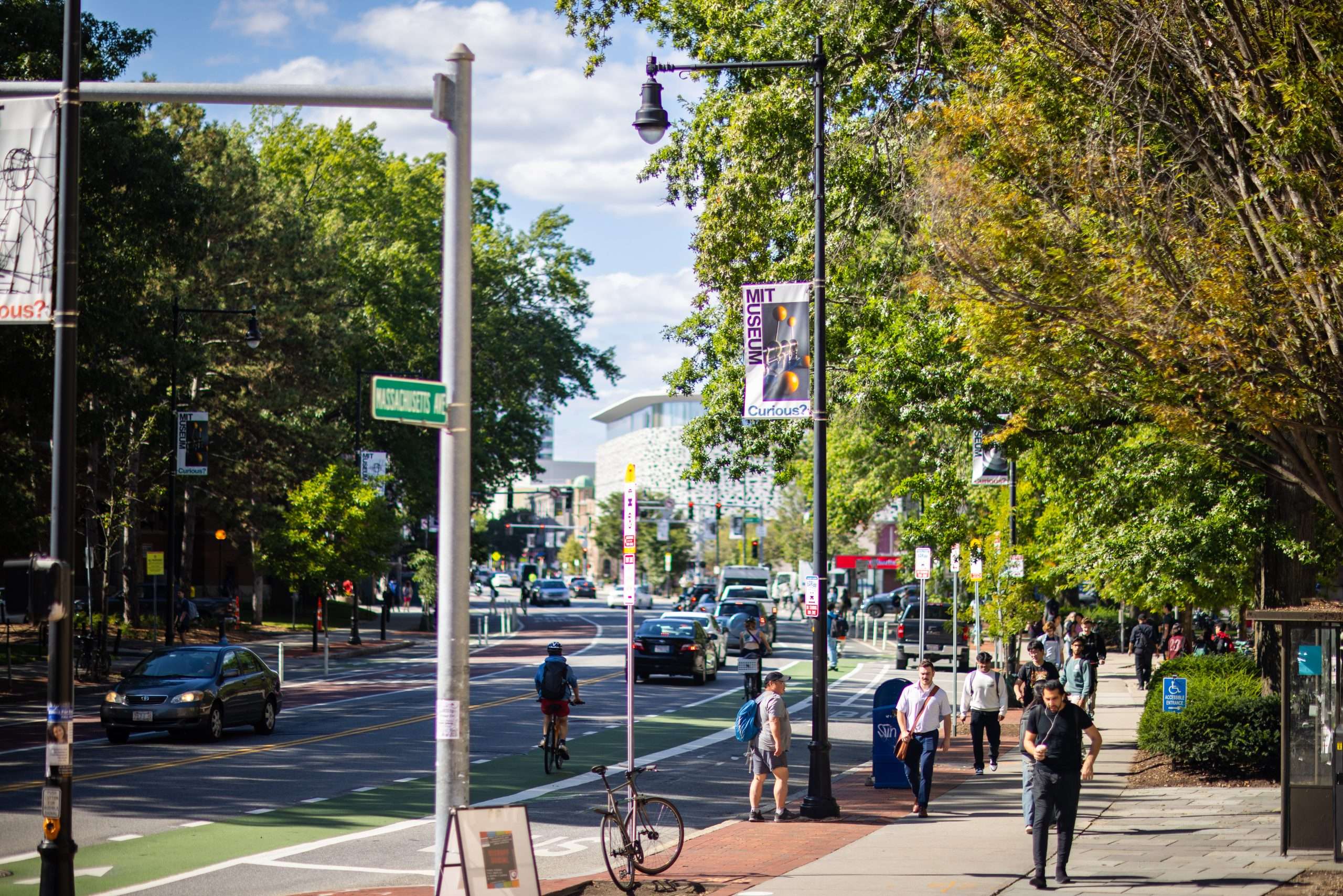 People walk on the sidewalk at MIT, beneath a banner for the MIT Museum.